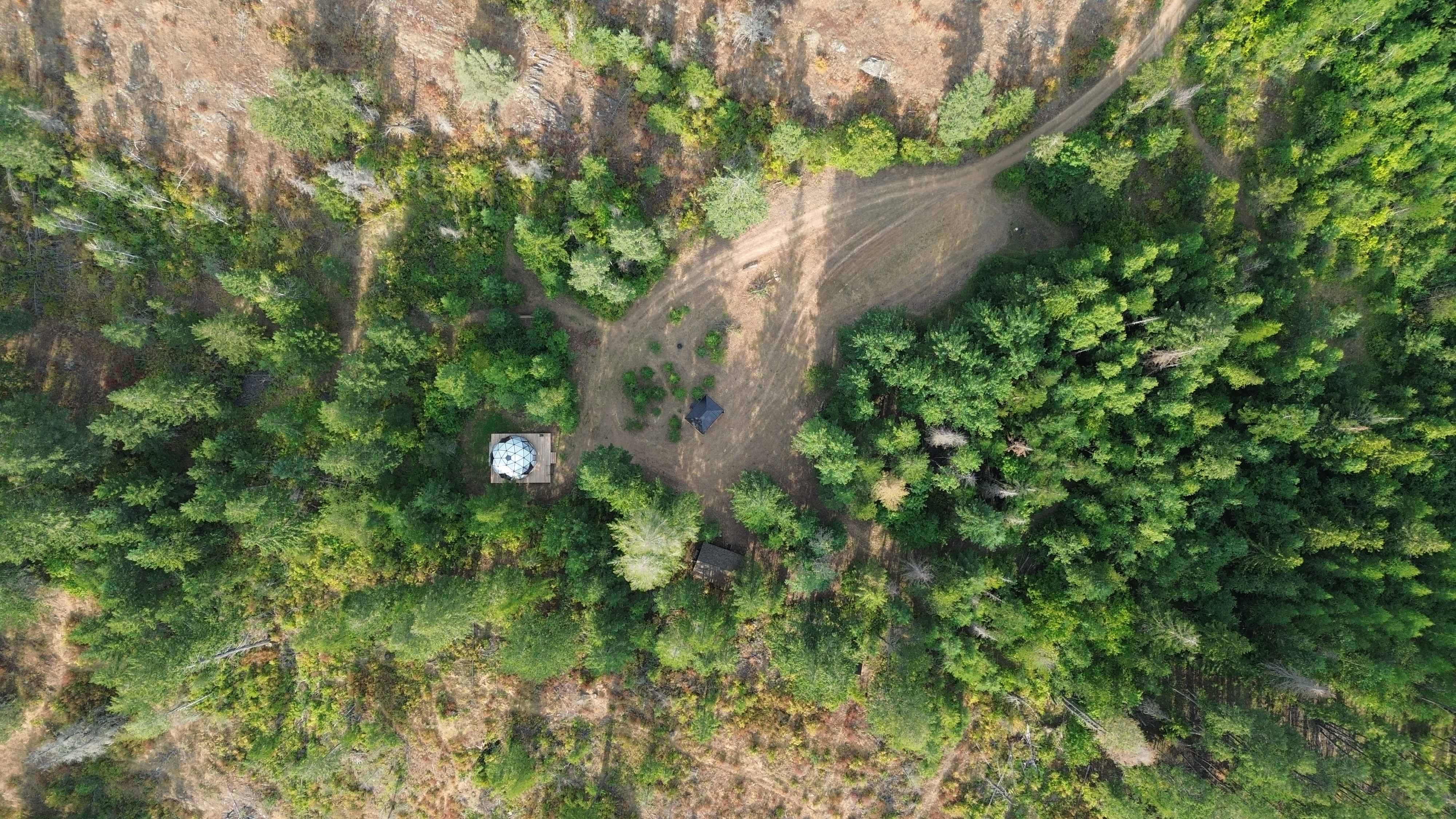Very high up drone shot looking directly down at the dome and camping area